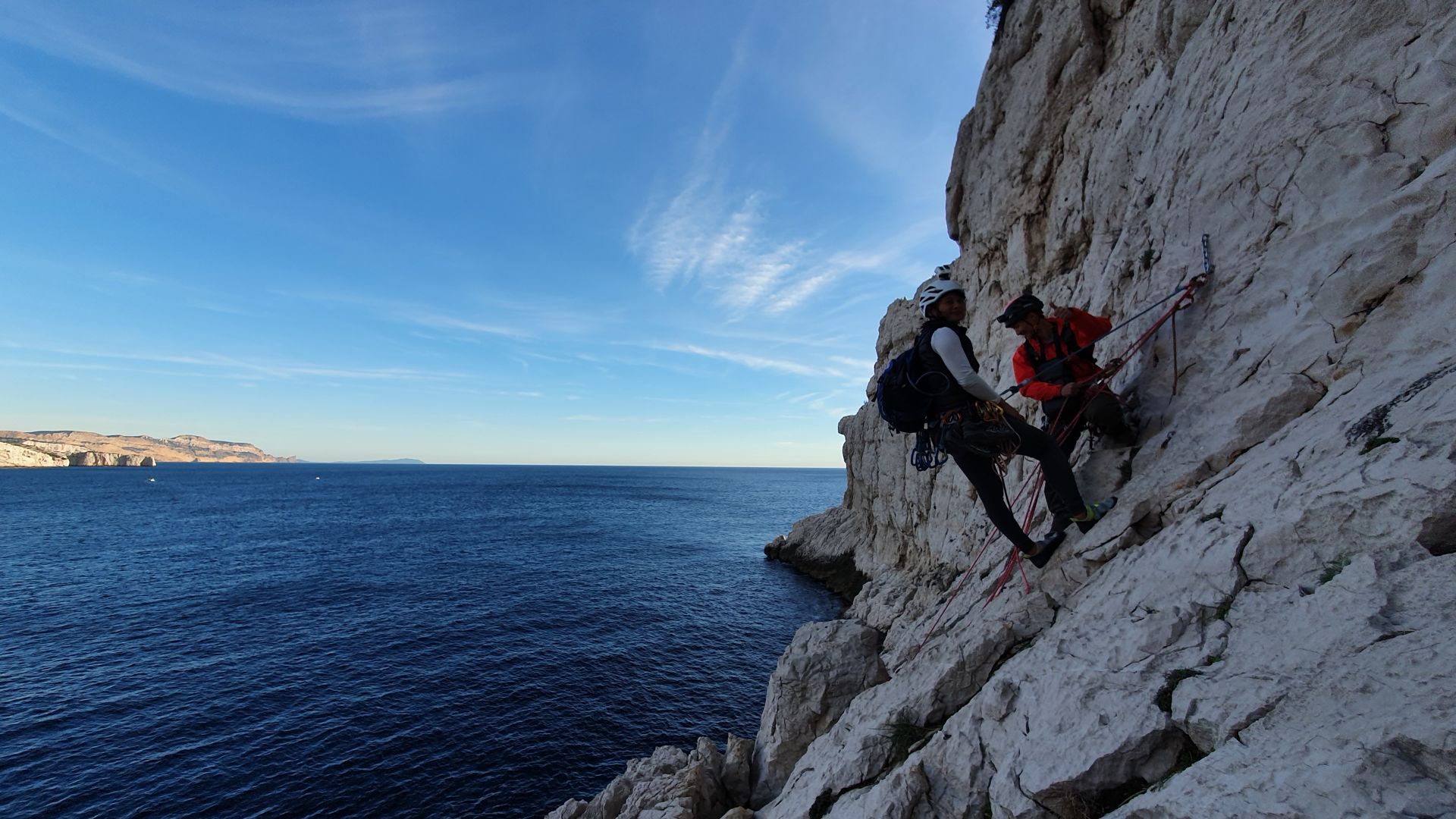Deux grimpeurs au relais d’une grande voie au-dessus de la mer